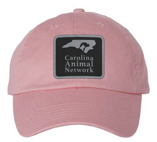 Pink dad hat featuring the Carolina Animal Network logo in a black and silver leatherette patch. Front view.