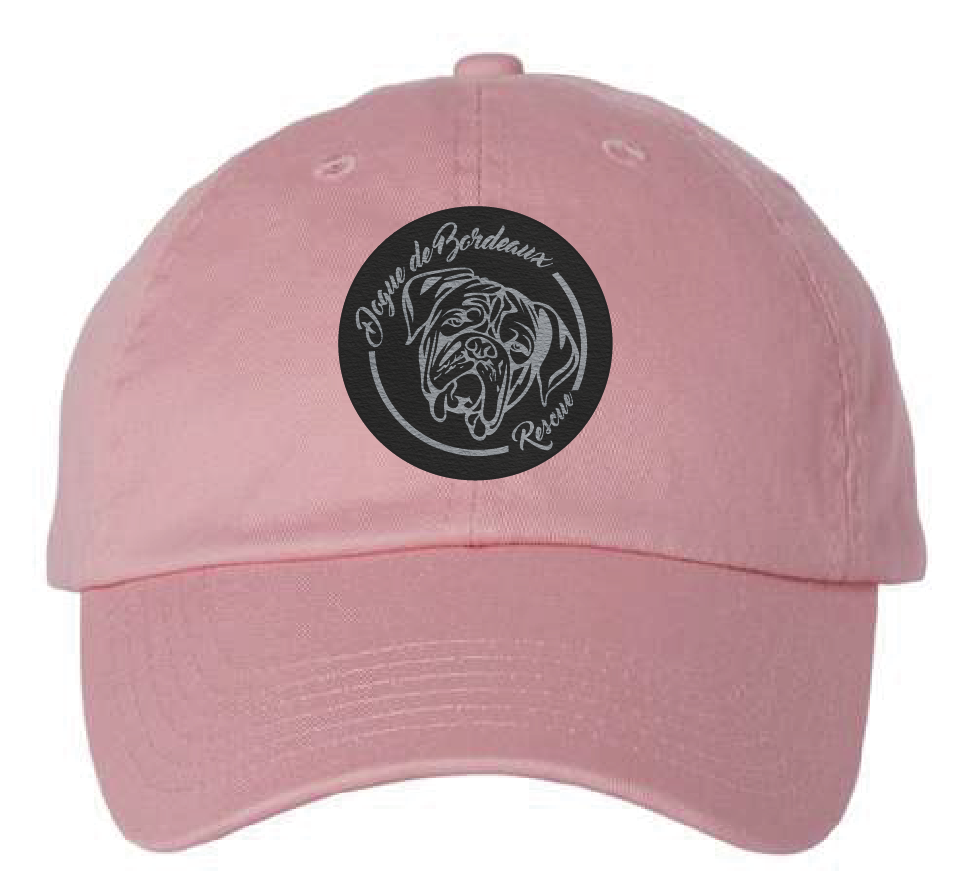 Pink dad hat featuring the Dogue de Bordeaux logo in a black and silver leatherette patch. Front view.